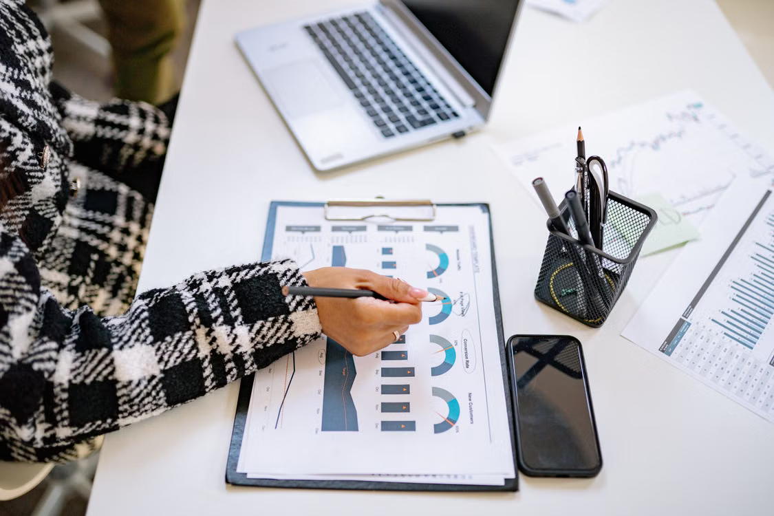 kenson Investments | What Institutional Blockchain Adoption Means for Digital Asset Education A person reviewing financial charts and blockchain research materials at a desk.