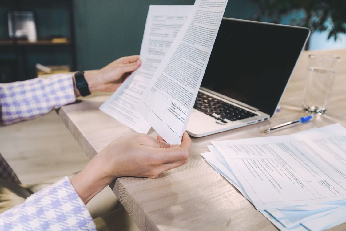 A person reviewing a printed legislative document at a desk with a laptop nearby. Caption: Reading primary legislative text remains one of the most reliable ways to separate fact from speculation in cryptocurrency investment strategies discussions.