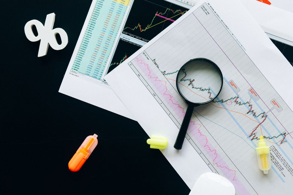 A magnifying glass positioned over a digital asset market chart, representing careful due diligence.