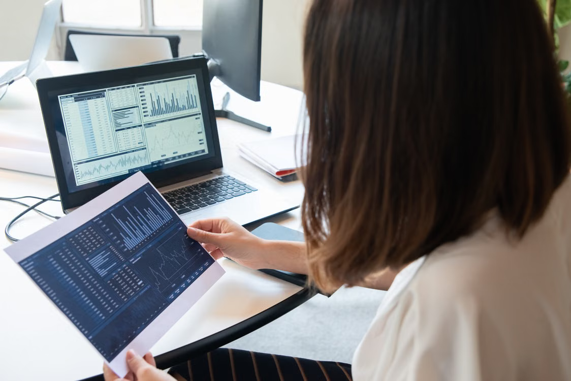 Financial analysts reviewing blockchain settlement data on office computer screens
