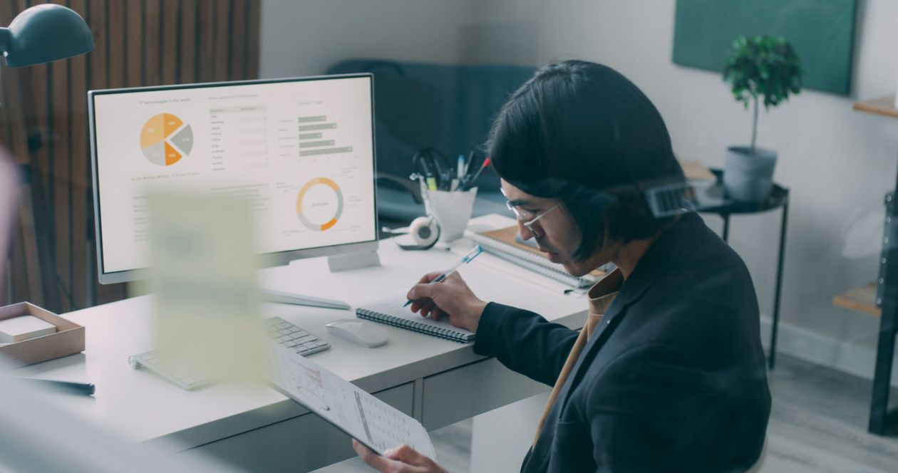 kenson Investments | How Tokenization Is Expanding Blockchain's Real-World Applications A person reviewing blockchain technology charts and educational materials at a desk