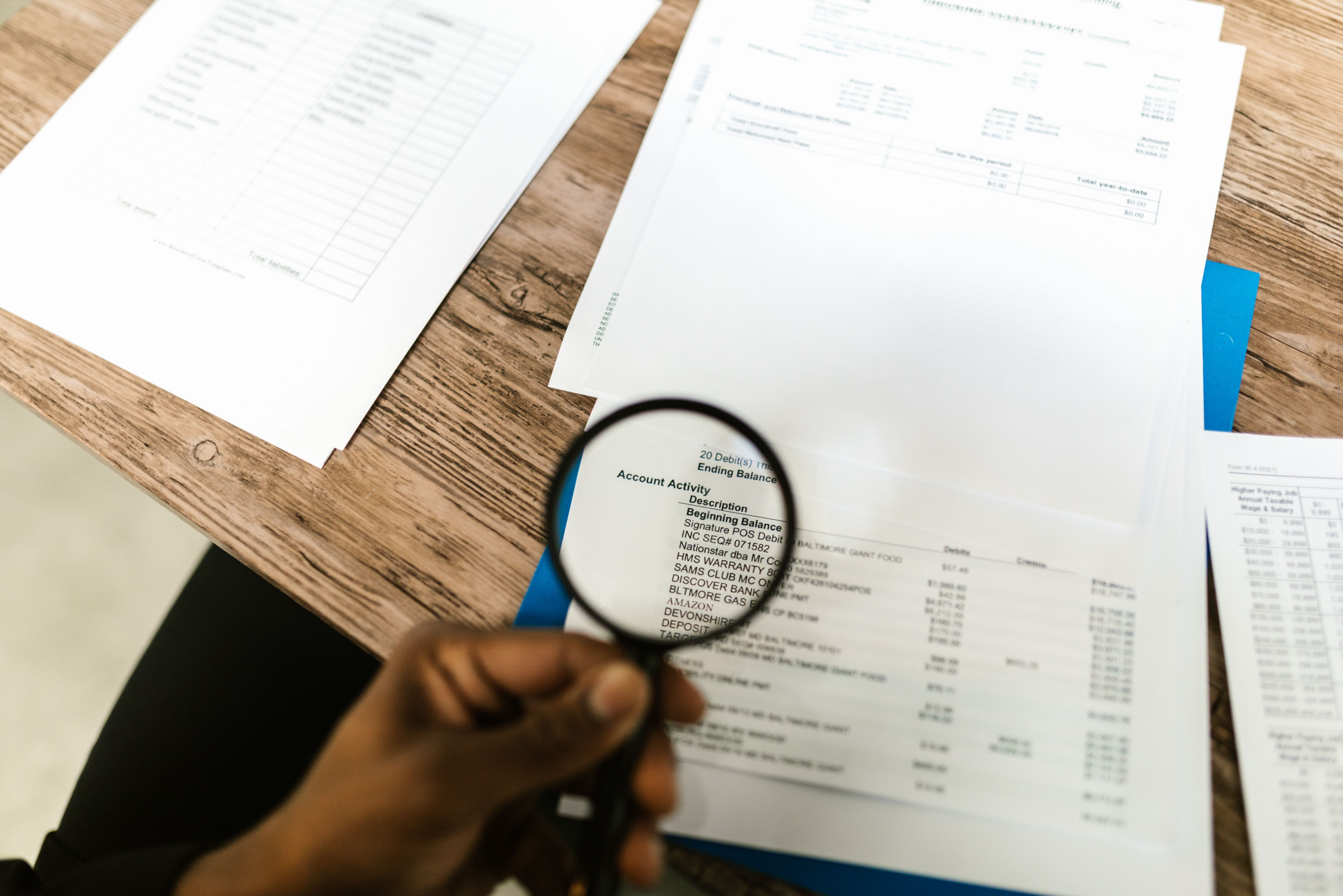 kenson Investments | The SEC Is Moving Before Congress: What a Tailored Crypto Offering Regime Could Actually Change Person examining financial documents with a magnifying glass during a detailed regulatory review.