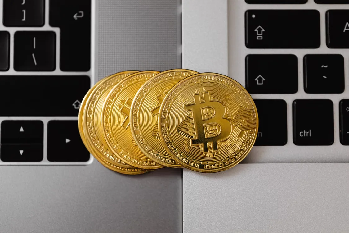 Close-up of Bitcoin coins resting on two laptop keyboards
