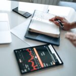 Financial professional analyzing securities market data on a computer while taking notes