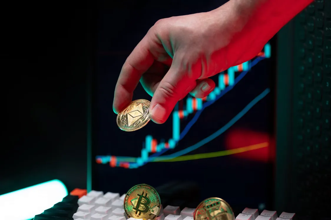 A hand holding cryptocurrency coins with a financial chart in the background