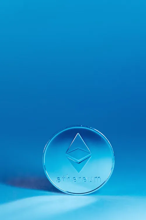 A close-up of an Ethereum coin against a vivid blue background