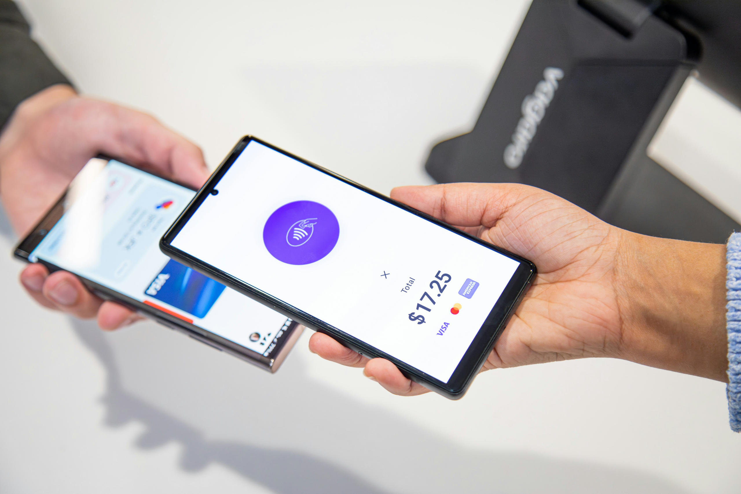 Customer completing a mobile payment with a smartphone at a business counter