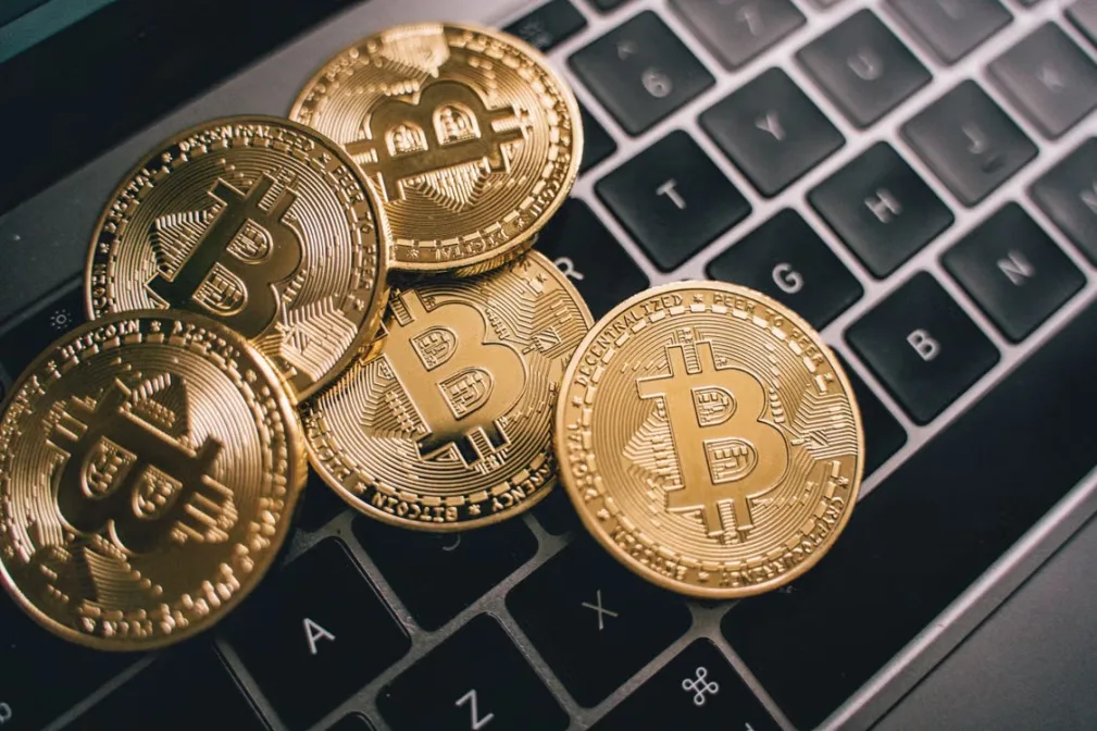 kenson Investments | Bitcoin Transaction Replacement: Fees, Conflicts, and Pinning Bitcoin coins placed on a laptop keyboard.