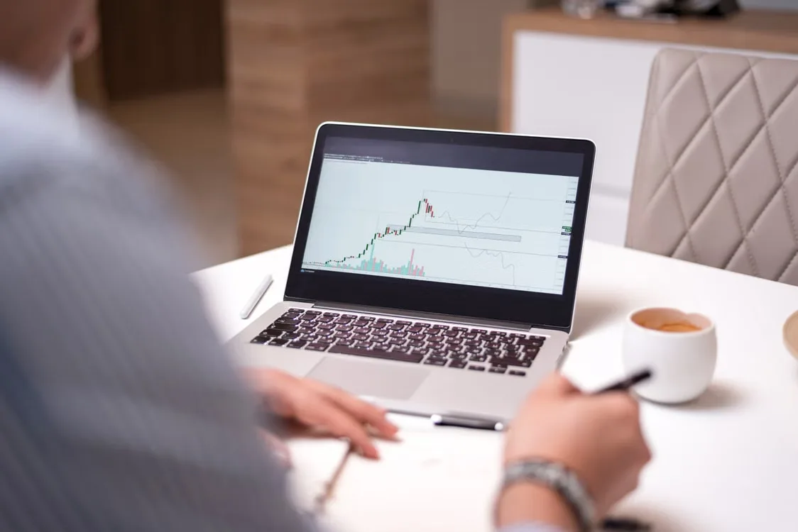 A person comparing a cryptocurrency company's public claims with official regulatory records displayed on a laptop.