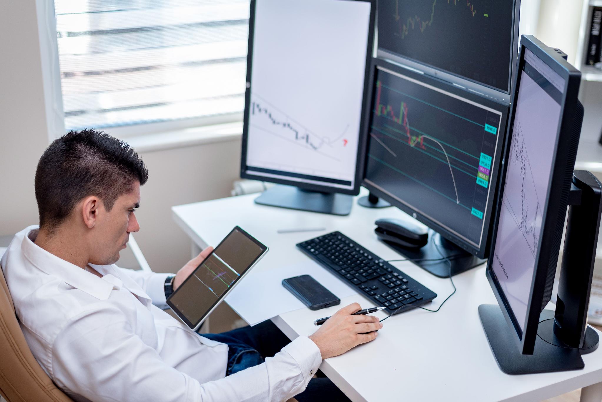 Professional trader monitoring financial market data across multiple screens