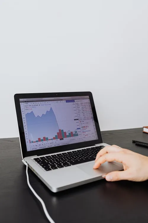 A desk workspace with a laptop displaying cryptocurrency market charts