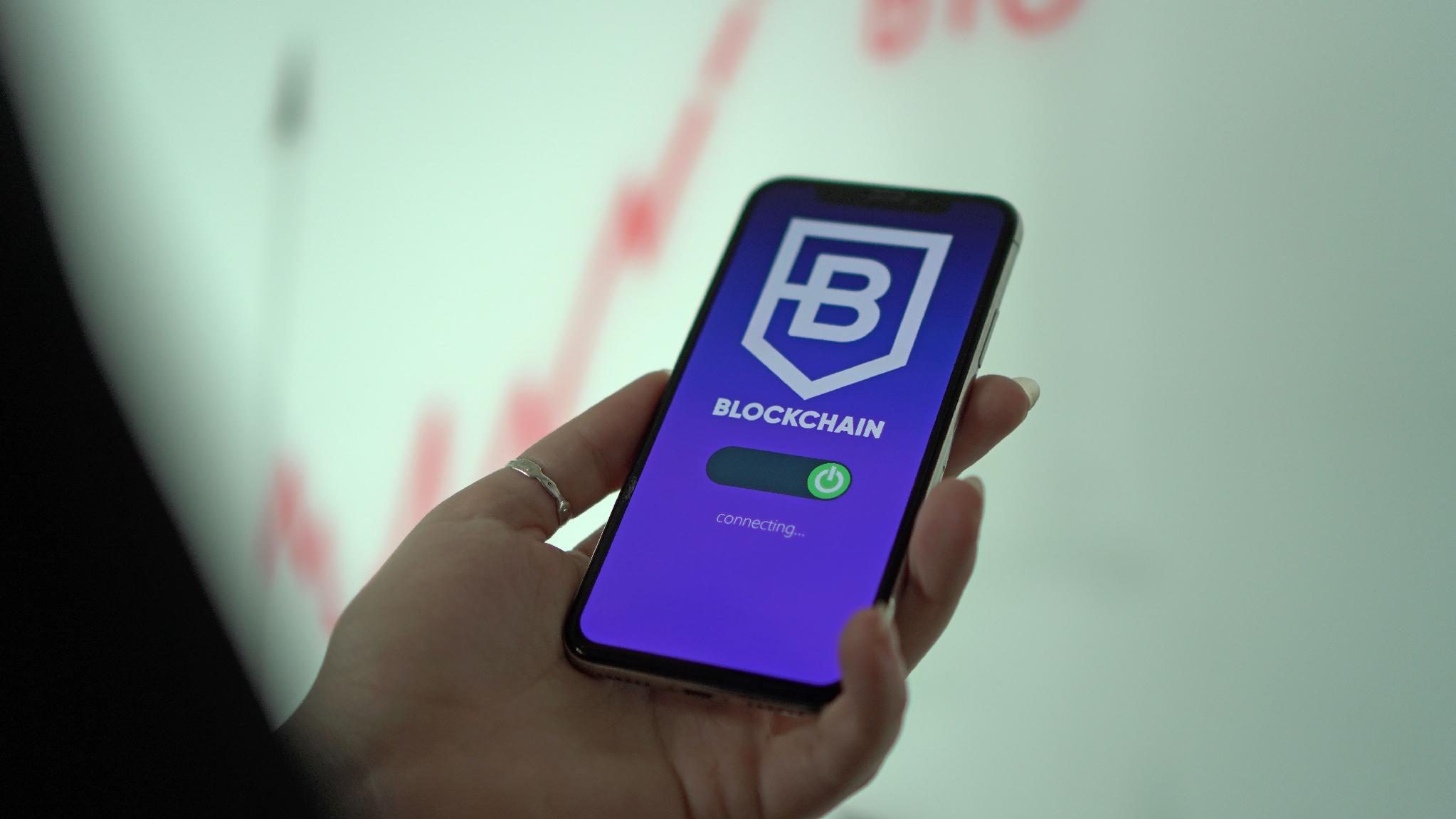Hand holding a smartphone displaying a cryptocurrency wallet used to interact with digital assets