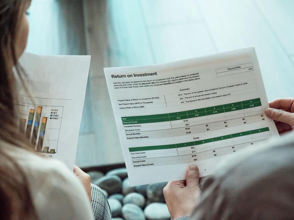 Financial professionals examining investment performance documents and financial calculations.