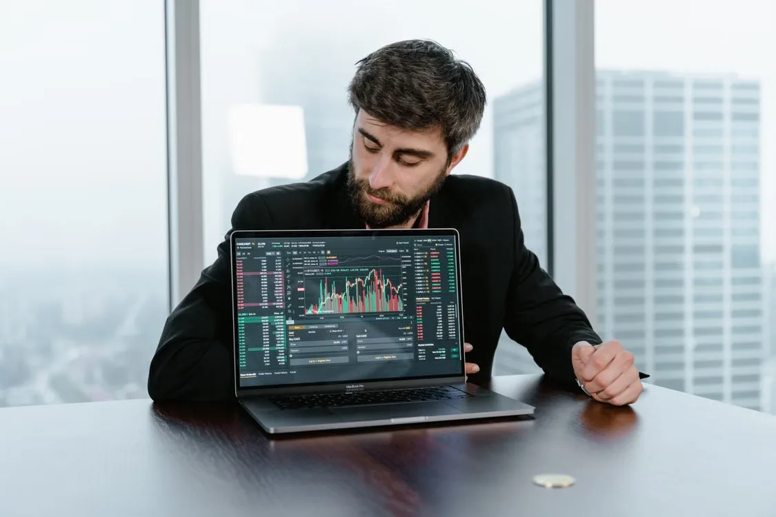 kenson Investments | Self-Trade Prevention: Cancel-Maker, Cancel-Taker, and Decrement Rules Man in a black suit reviewing information on a laptop.