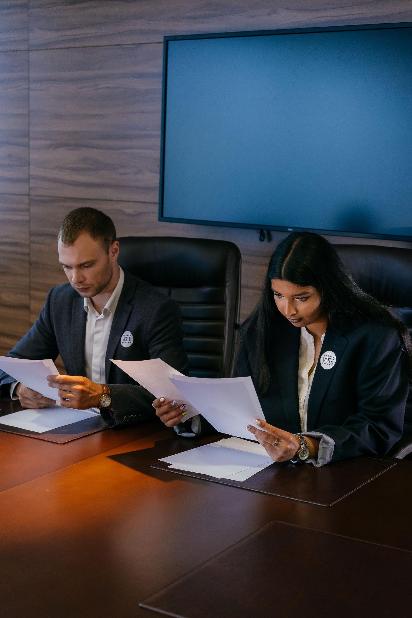 Business professionals reviewing regulatory and financial documents during an institutional meeting