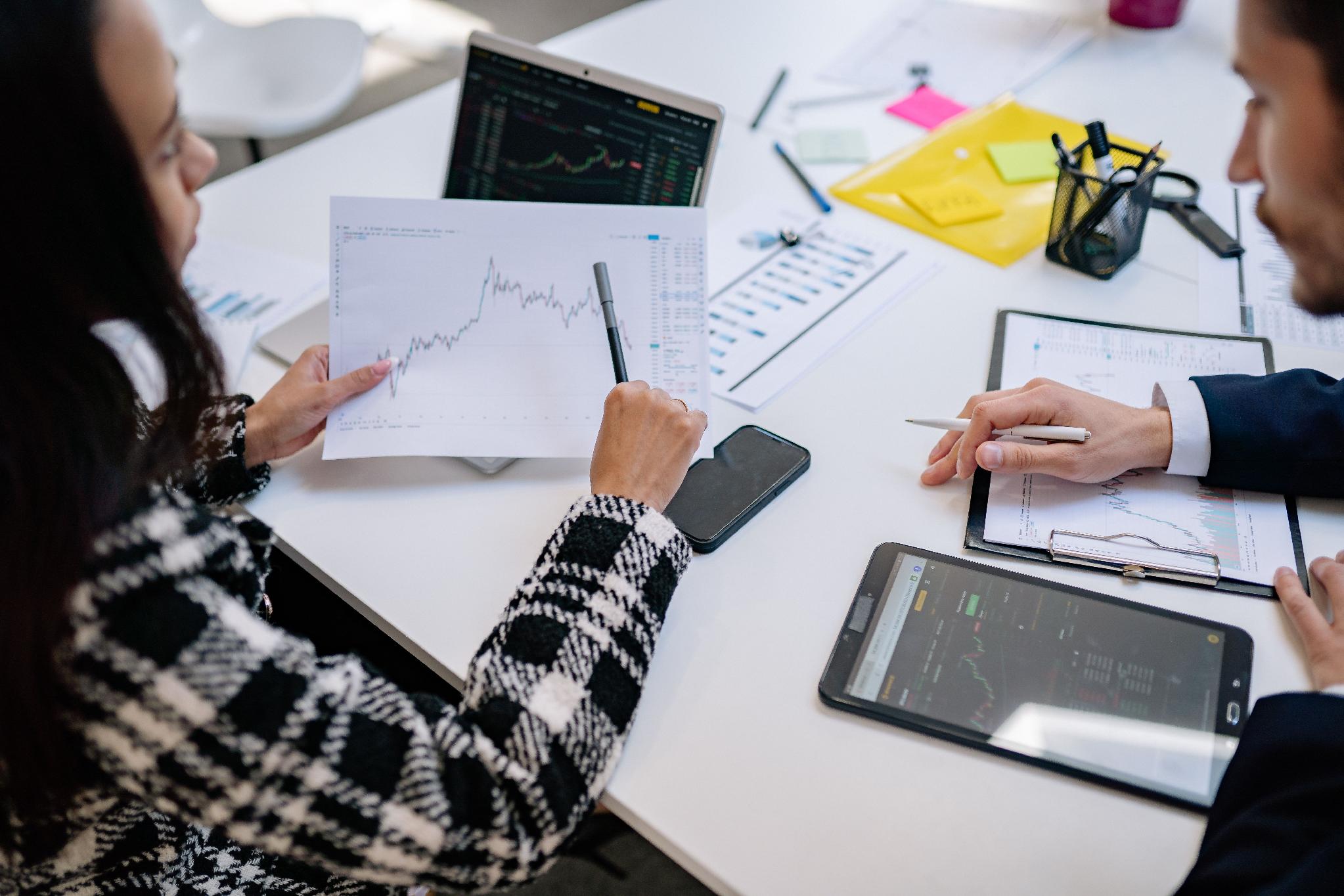 Investment professionals reviewing financial reports and market data during an office meeting