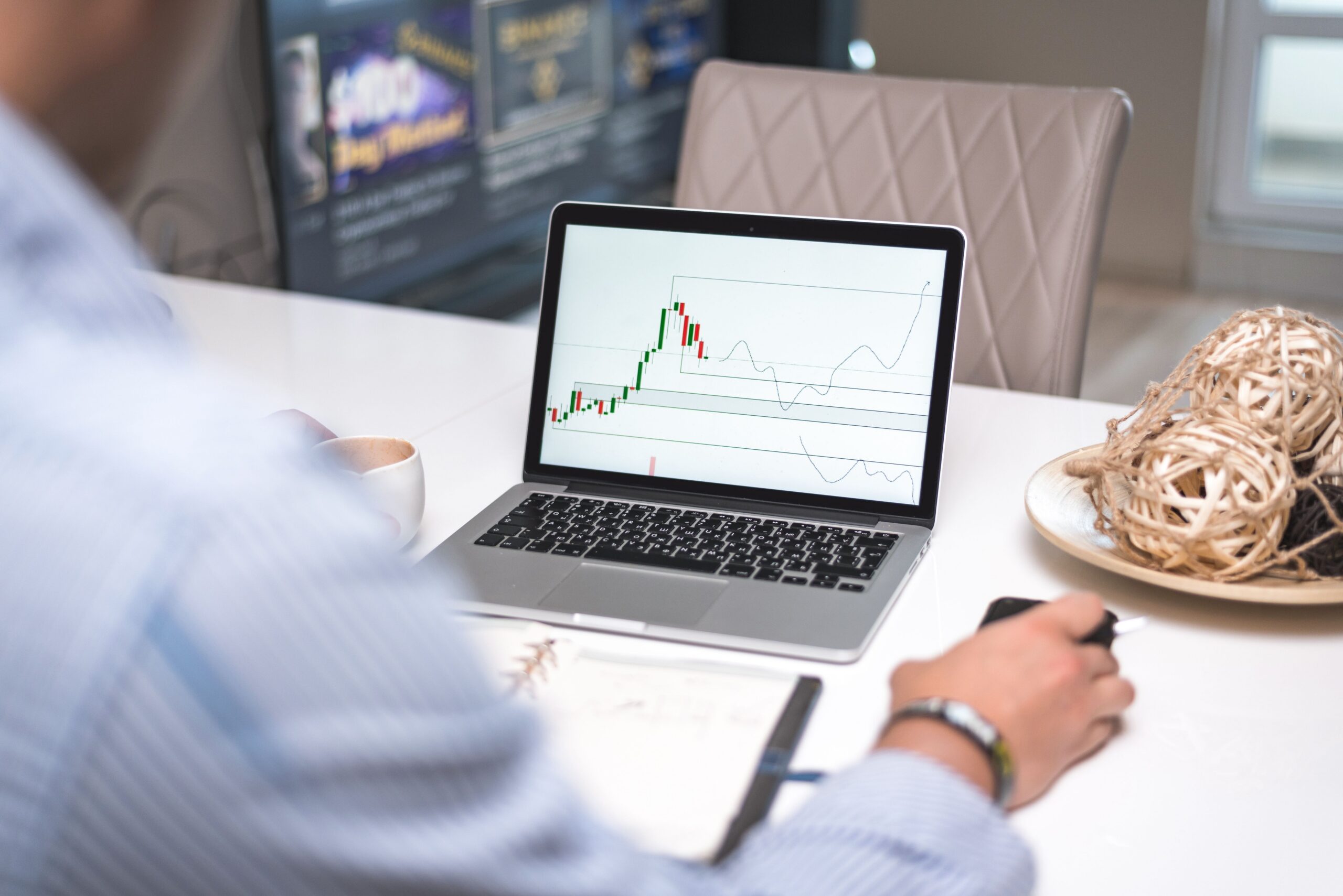 Financial analyst monitoring trading charts and market data on a laptop.