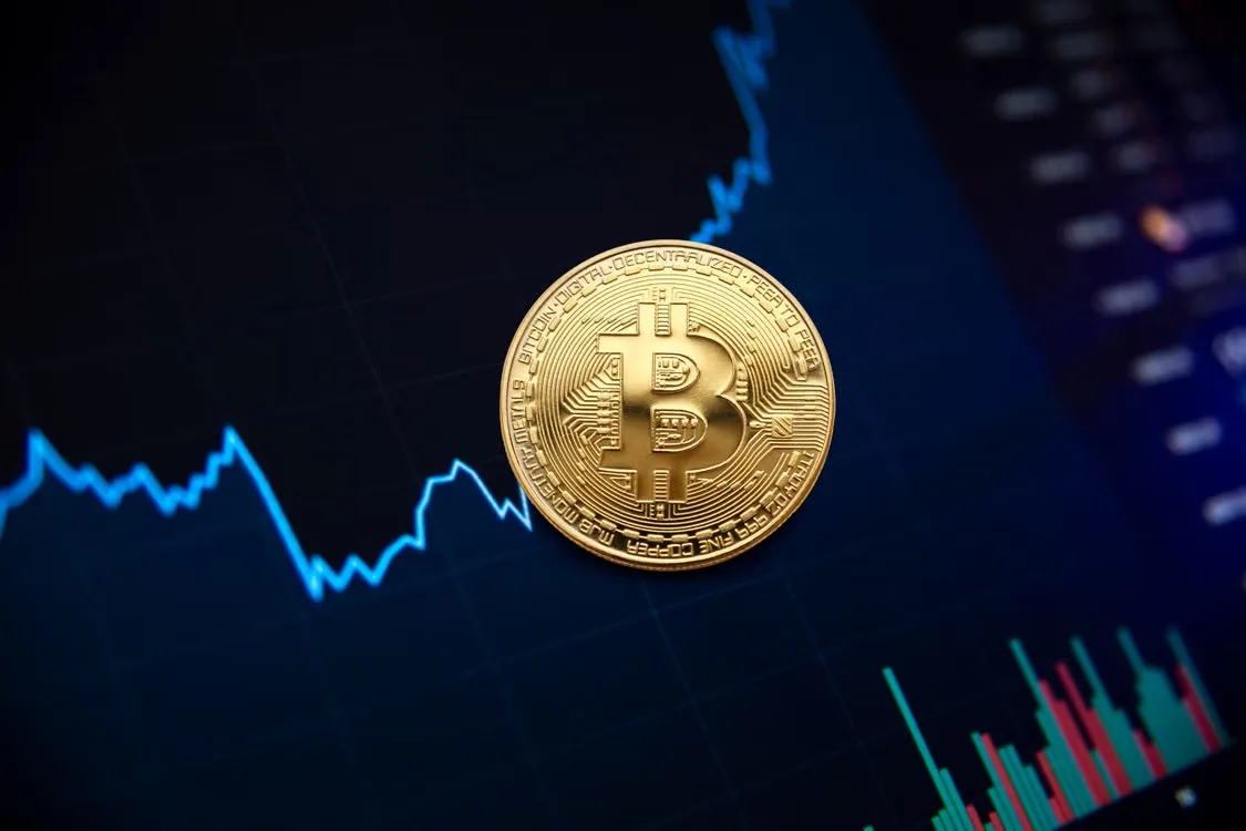 kenson Investments | Crypto Vaults Explained: Five Risks to Understand Before Evaluating Digital Asset Lending Golden bitcoin coin displayed against a digital stock market chart