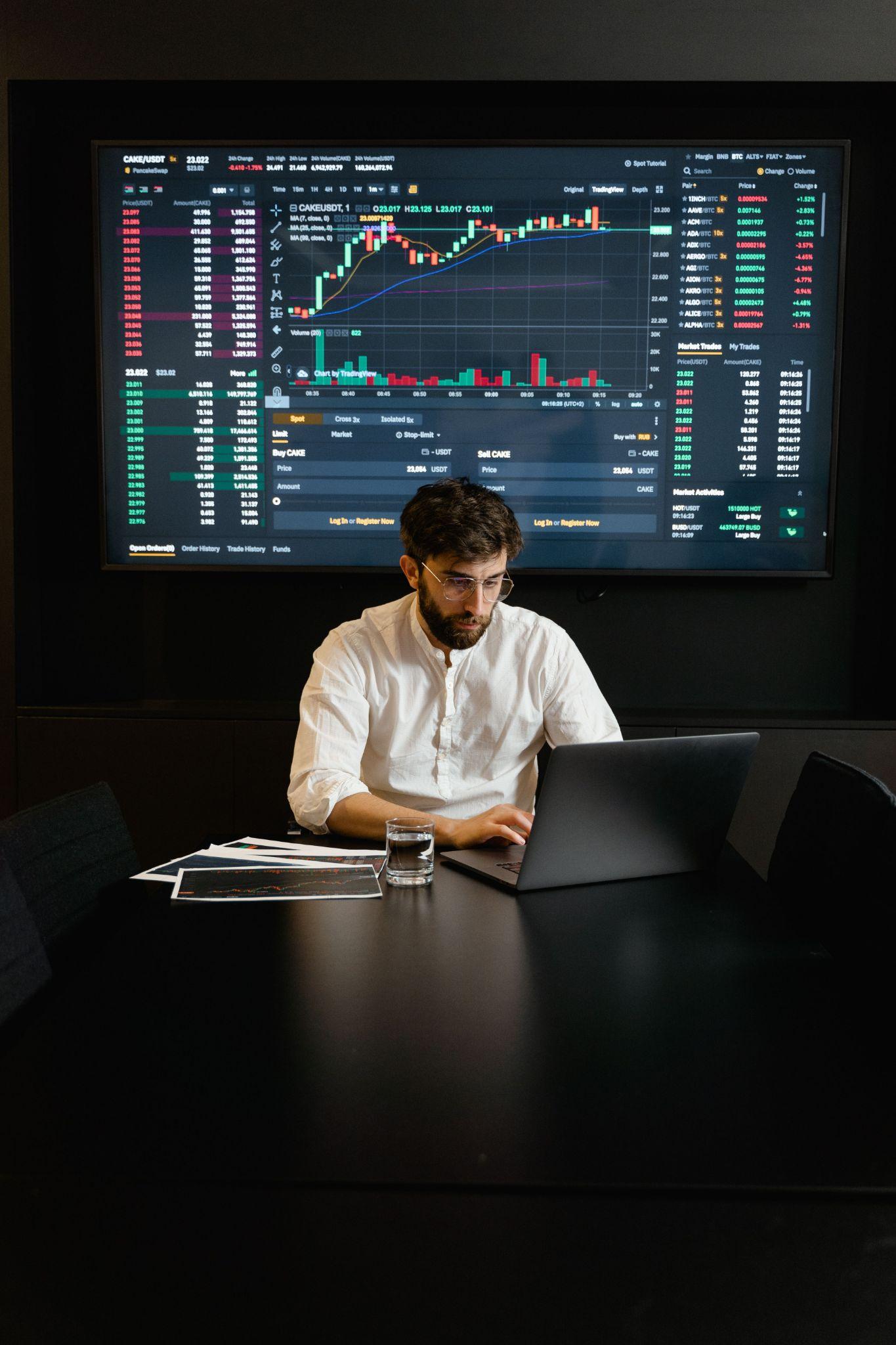 Finance professional reviewing financial market data and digital asset charts on a laptop