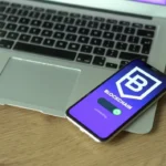 Smartphone displaying blockchain application resting on a laptop, symbolizing modern technology and finance.