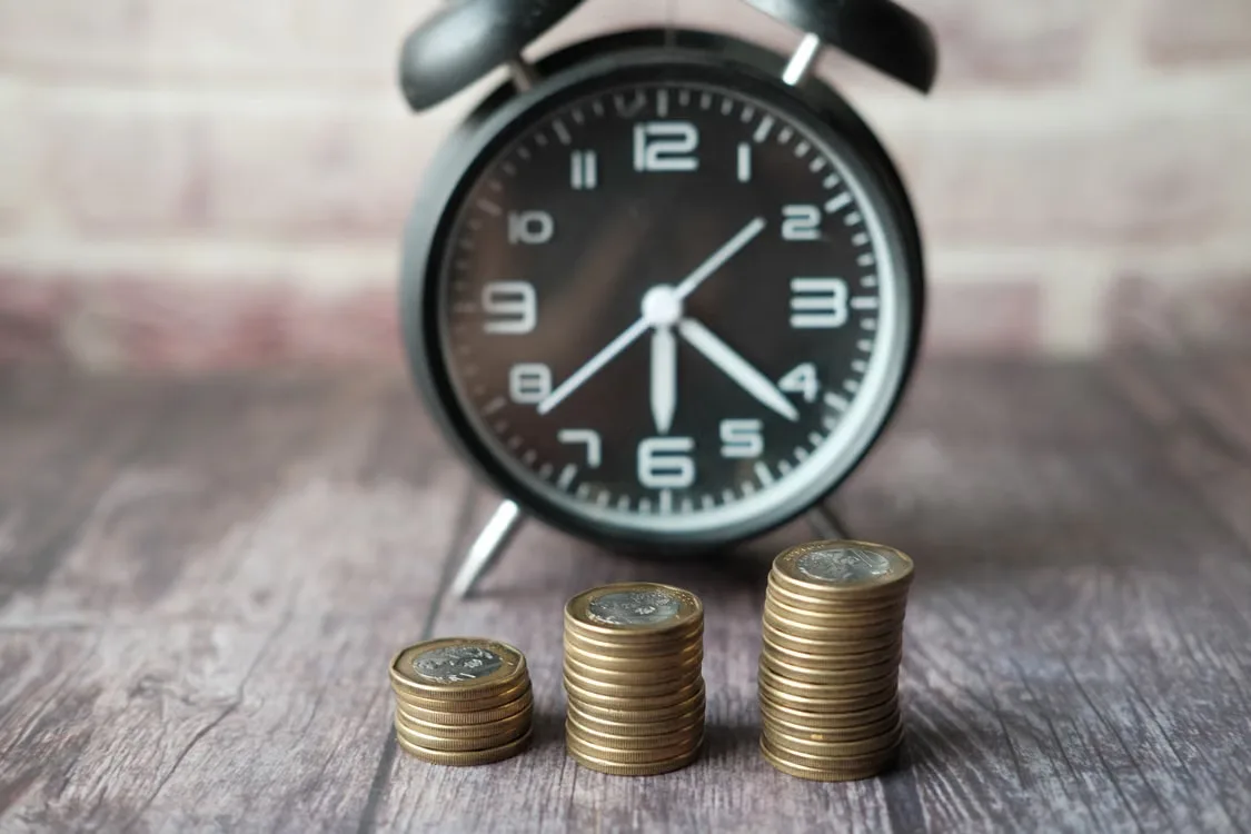 kenson Investments | Fiduciary Review of Digital and Alternative Assets in Retirement Plan Menus Stacks of coins beside an alarm clock.