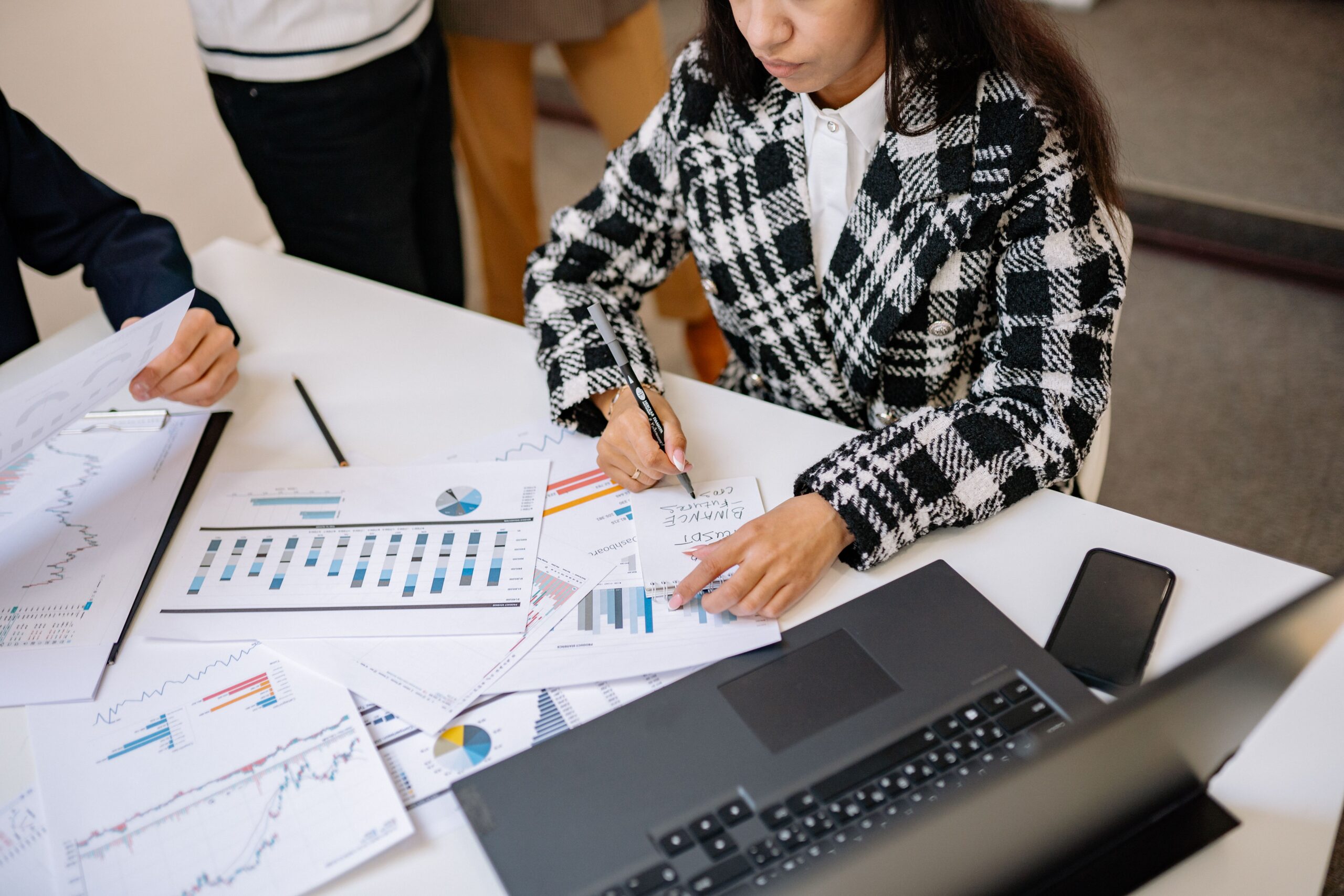 Investment professionals reviewing financial charts and market analysis documents together in an office.