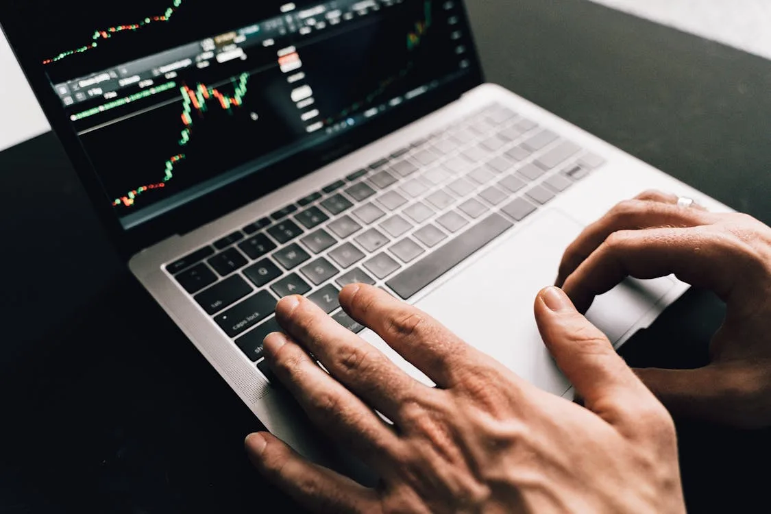 Person analyzing digital asset charts on a laptop representing on-chain supply concentration and entity-adjusted market analysis.